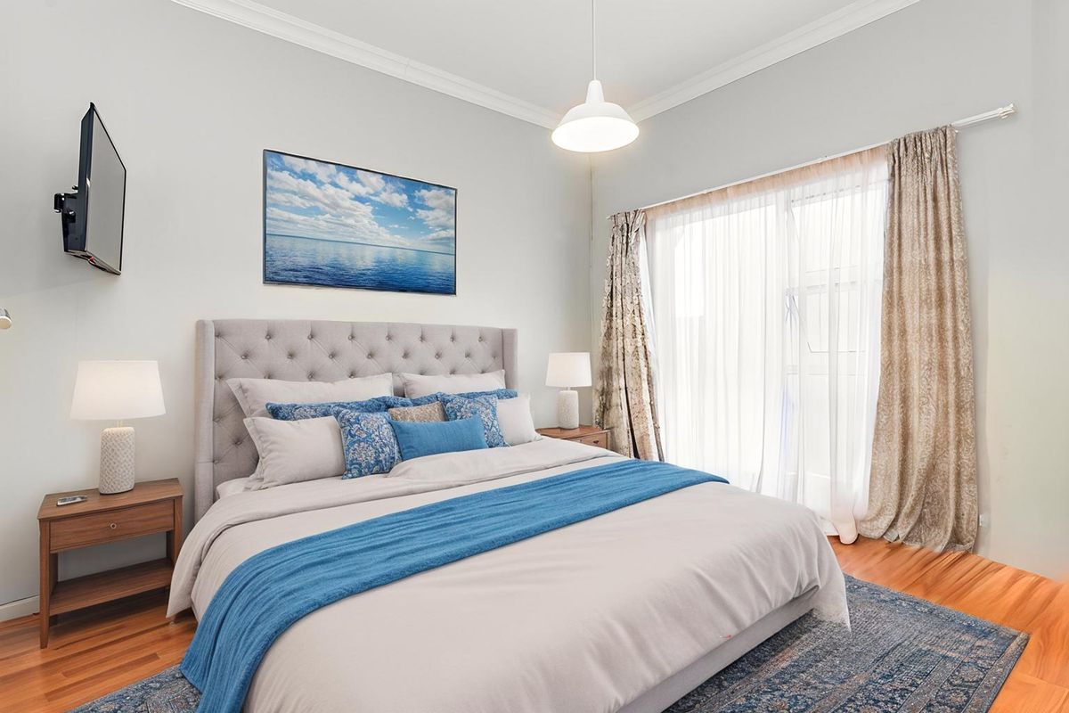 A well-maintained bedroom featuring hardwood flooring, crown molding, and a sliding glass door providing access to an outdoor area.