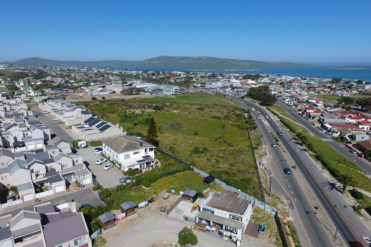 Aerial view of the guest house property, showcasing its location near the main road, surrounding residential area, and coastal landscape.