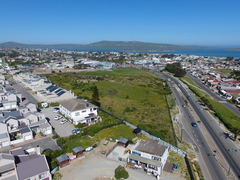 Aerial view of the guest house property, showcasing its location near the main road, surrounding residential area, and coastal landscape.