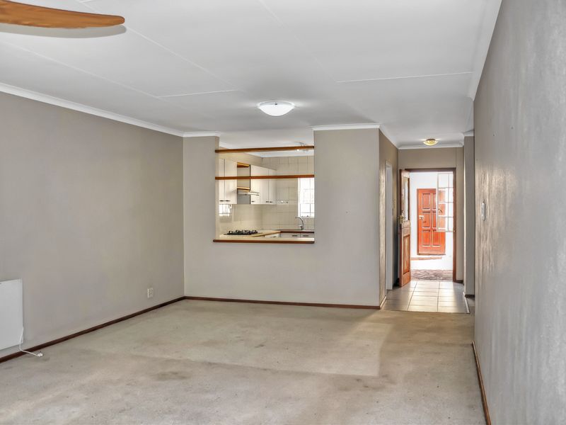 Open plan living area featuring a pass-through window to the kitchen, neutral wall tones, and direct access to the front entrance.