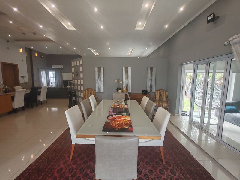 Spacious open-plan dining and living area featuring modern recessed ceiling lighting, large format floor tiles, and expansive sliding glass doors leading to the outdoors.