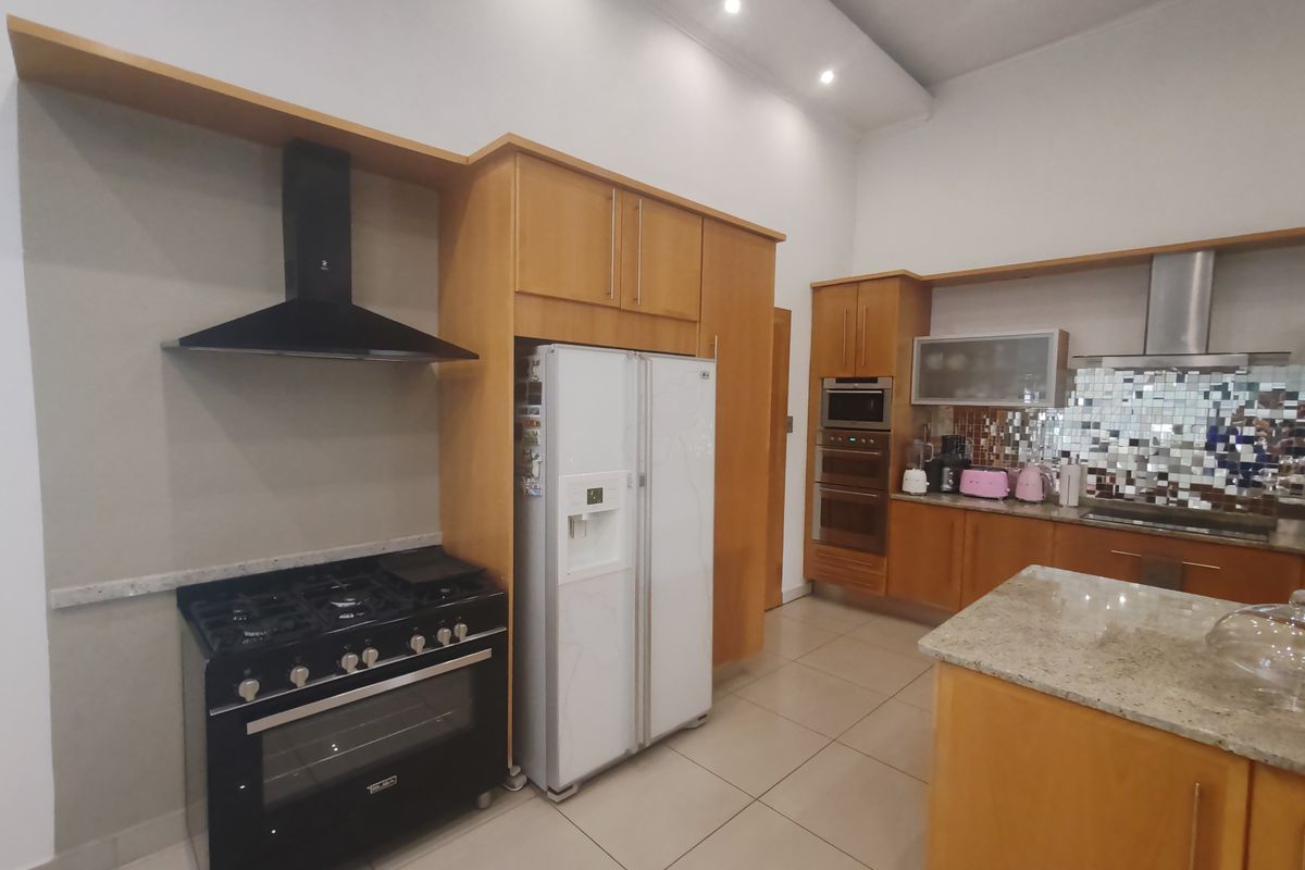 Spacious kitchen featuring light wood cabinetry, granite countertops, a central island, and built-in appliances including a gas stove and oven.
