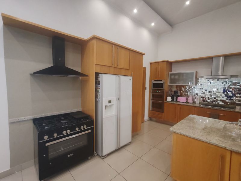 Spacious kitchen featuring light wood cabinetry, granite countertops, a central island, and built-in appliances including a gas stove and oven.