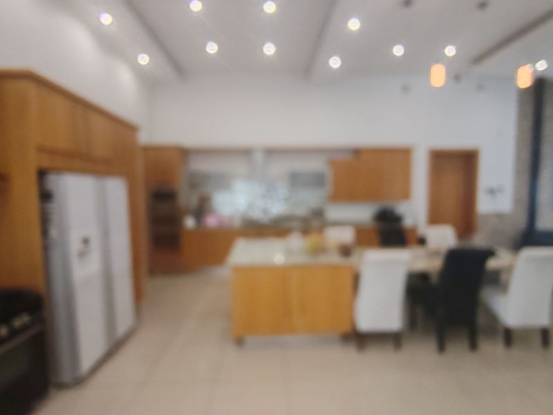 An open-plan kitchen and dining area featuring wooden cabinetry, a central island, and recessed ceiling lighting.
