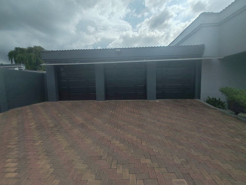 A triple garage with dark-finished doors and a paved driveway, presenting a clean and well-maintained exterior facade.