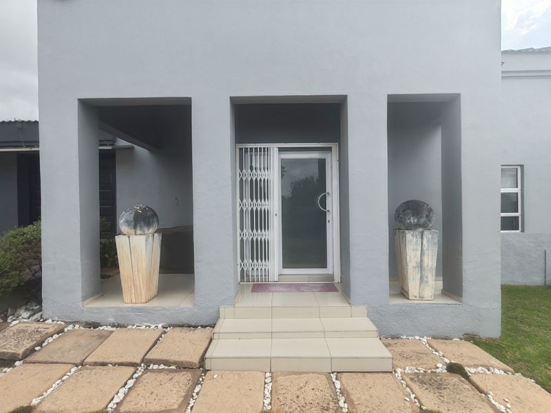 Front entrance featuring a security gate, tiled porch area, and stone paver walkway leading to the main door.