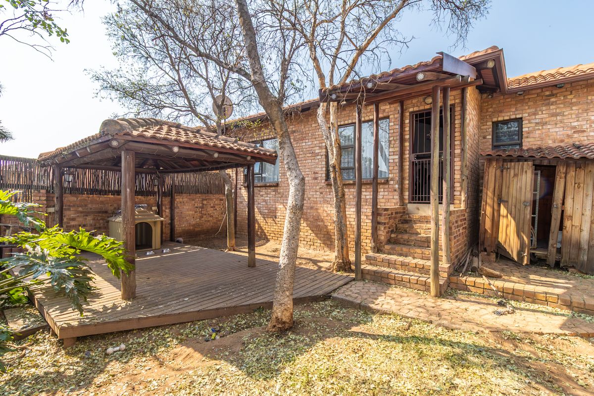 Rear exterior view featuring a brick facade, a wooden gazebo with a deck, and a paved patio area leading to the entrance.