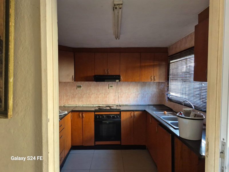 A functional kitchen featuring wood-tone cabinetry, built-in oven and hob, tiled backsplash, and double sink, offering potential for a modern renovation.