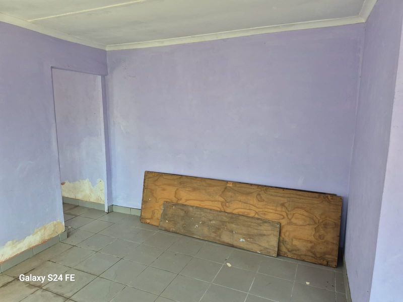 An empty room featuring ceramic floor tiles and coved cornicing, currently requiring wall repairs and repainting to restore its condition.
