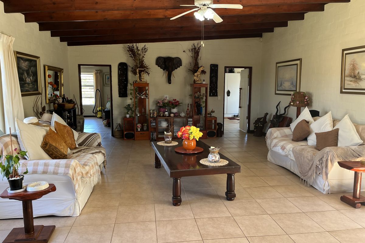 Spacious living room featuring exposed timber ceiling beams, a central ceiling fan, and neutral ceramic floor tiles throughout.