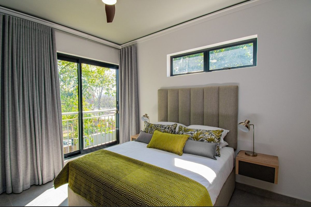 A well-appointed bedroom featuring a sliding glass door with balcony access, a horizontal clerestory window, and a ceiling fan.