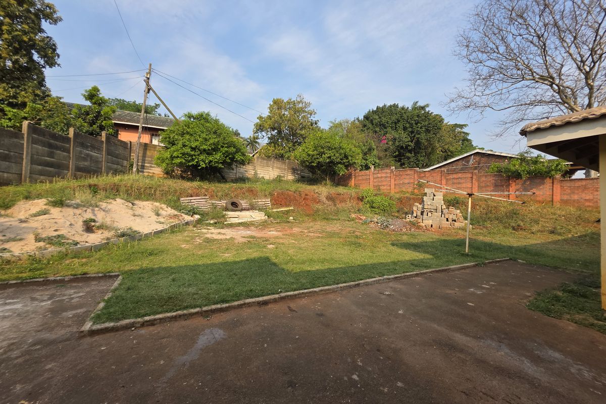 A spacious rear garden area featuring a concrete patio, boundary walls, and significant potential for landscaping and outdoor improvement.