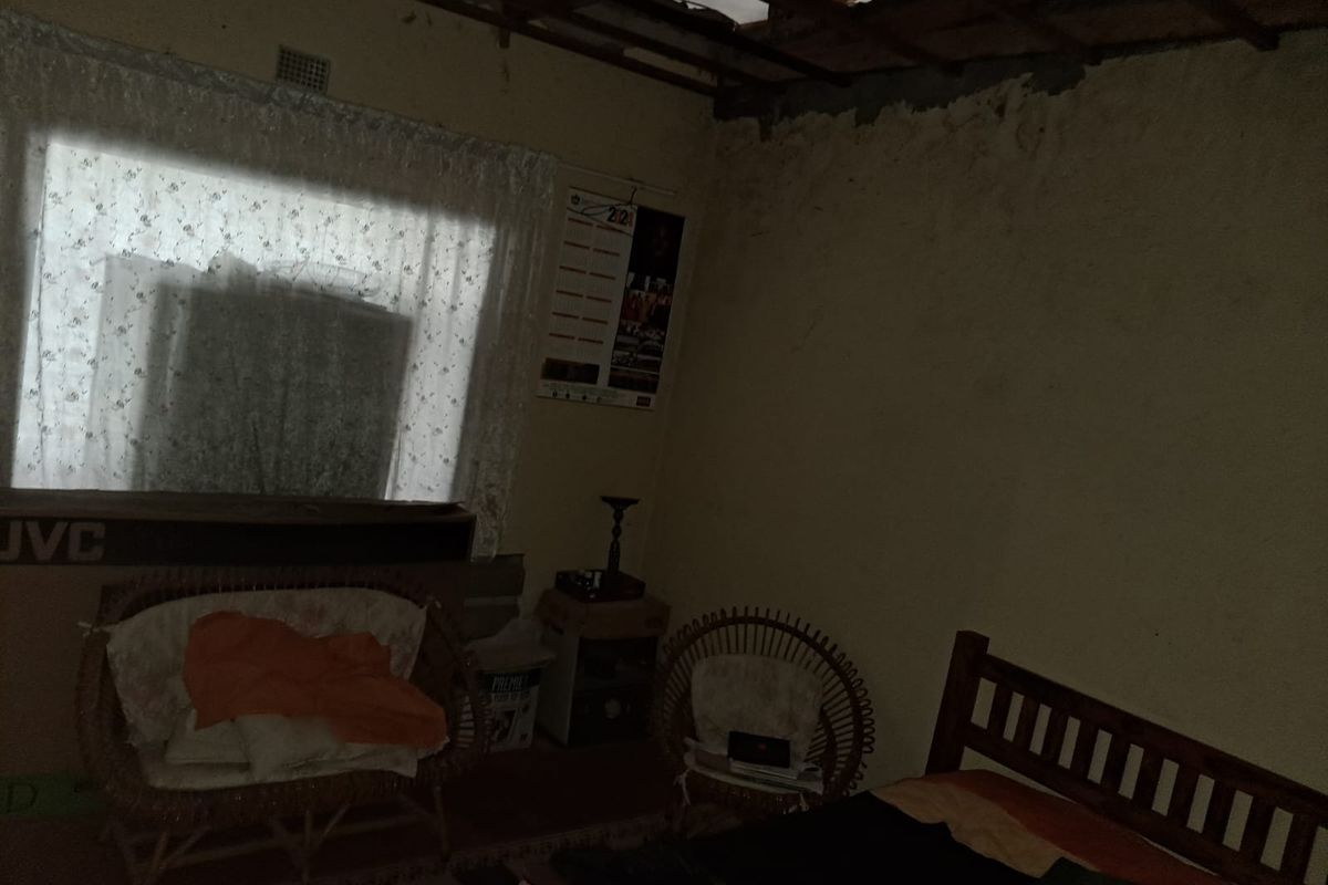 A bedroom interior showing significant structural damage to the ceiling and wall finishes, requiring major repairs and renovation.