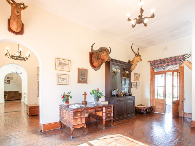 Spacious living area featuring original hardwood flooring, classic archways, and timber door access to the exterior, offering a traditional aesthetic.