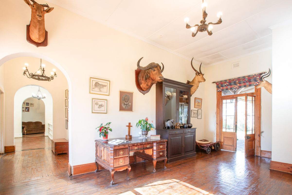 Spacious living area featuring original hardwood flooring, classic archways, and timber door access to the exterior, offering a traditional aesthetic.