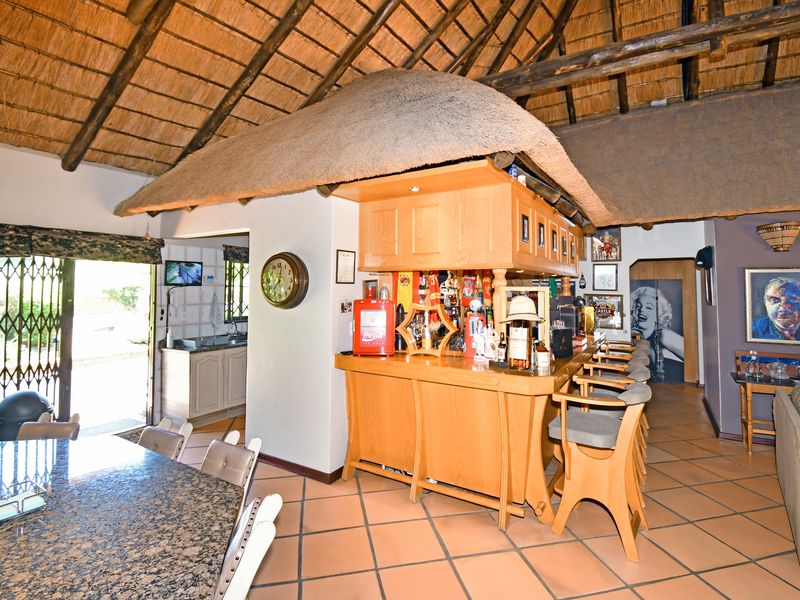 Spacious bar area featuring a traditional thatched roof with exposed timber beams, a built-in wooden bar counter, and durable tiled flooring.