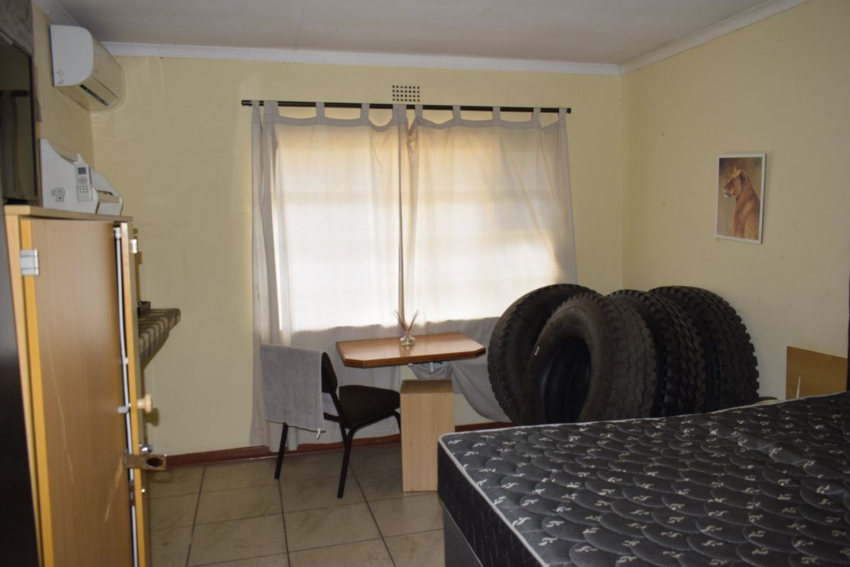 A bedroom featuring tiled flooring and a wall-mounted air conditioning unit, currently used as a multi-purpose space.