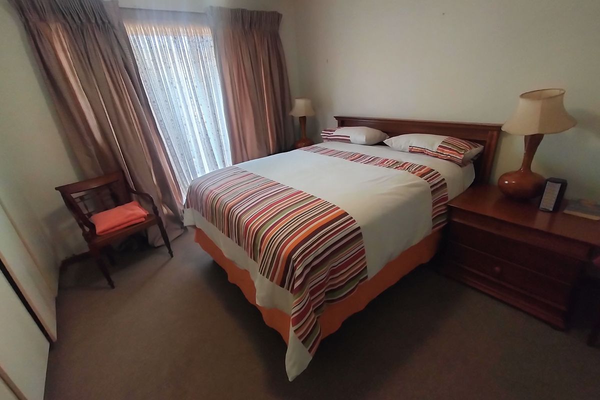 A functional bedroom featuring neutral carpeting, a built-in wardrobe, and a sliding glass door providing access to the exterior.