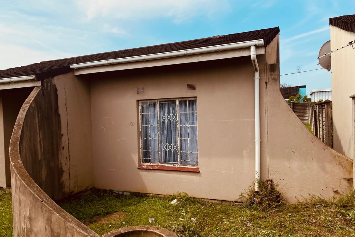 Exterior view of a residential property featuring a tiled roof, security-barred window, and concrete boundary wall, showing signs of wear and maintenance requirements.