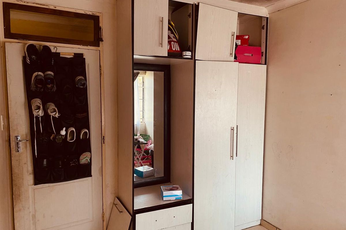 A bedroom featuring built-in cabinetry with integrated mirror and shelving, tiled flooring, and a standard entry door.