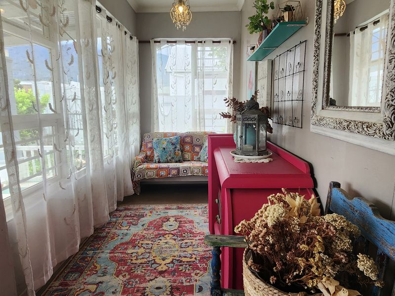 A sun-drenched enclosed patio or sunroom featuring large windows, providing a bright and inviting space for relaxation.