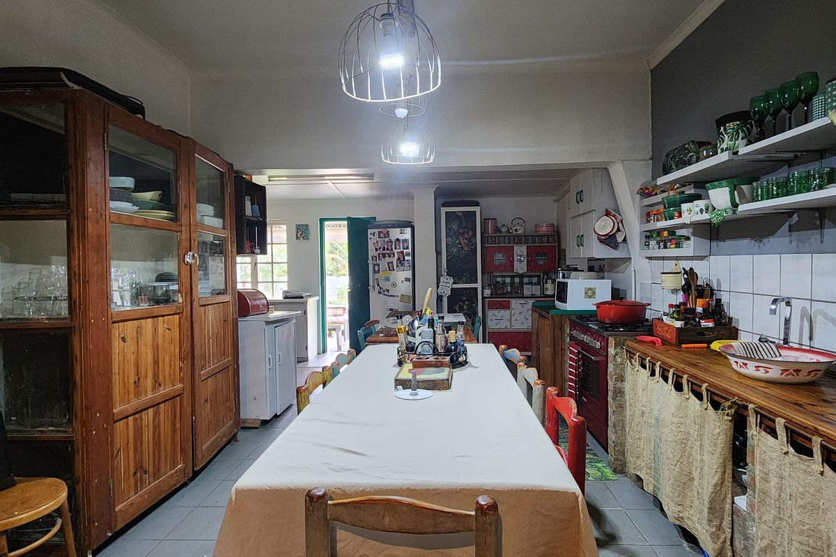A rustic kitchen featuring open shelving, tiled backsplash, and built-in cabinetry, offering a functional layout with potential for modern updates.