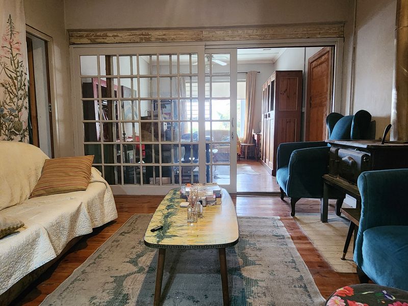 Cozy living room featuring hardwood flooring, a wood-burning stove, and sliding glass doors that provide natural light and access to the adjacent room.
