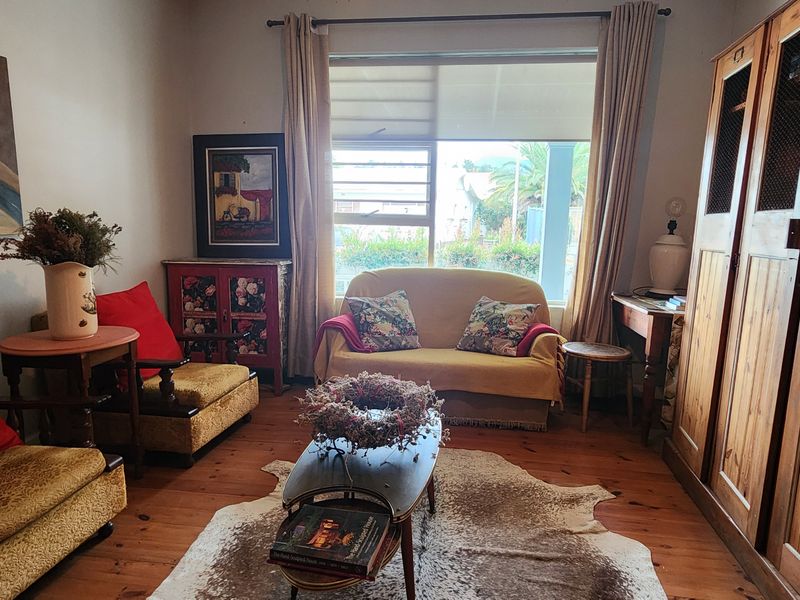 A cozy living room featuring warm timber flooring, large window for natural light, and extensive built-in wooden cabinetry for storage.