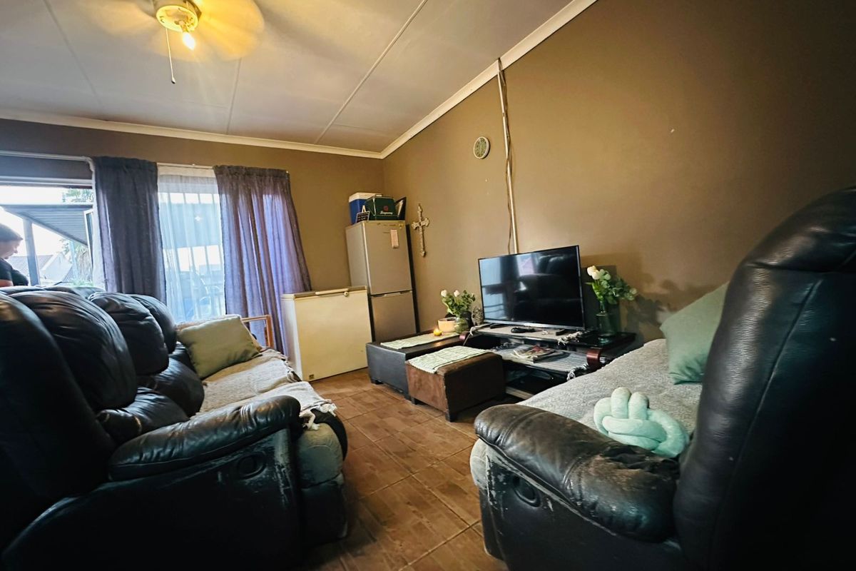 A living room featuring tiled flooring, a ceiling fan, and direct access to an outdoor patio area.