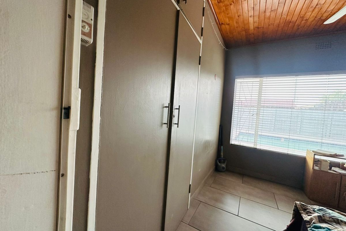 Bedroom featuring built-in cupboards, tiled flooring, and a timber-clad ceiling with a view of the pool area.