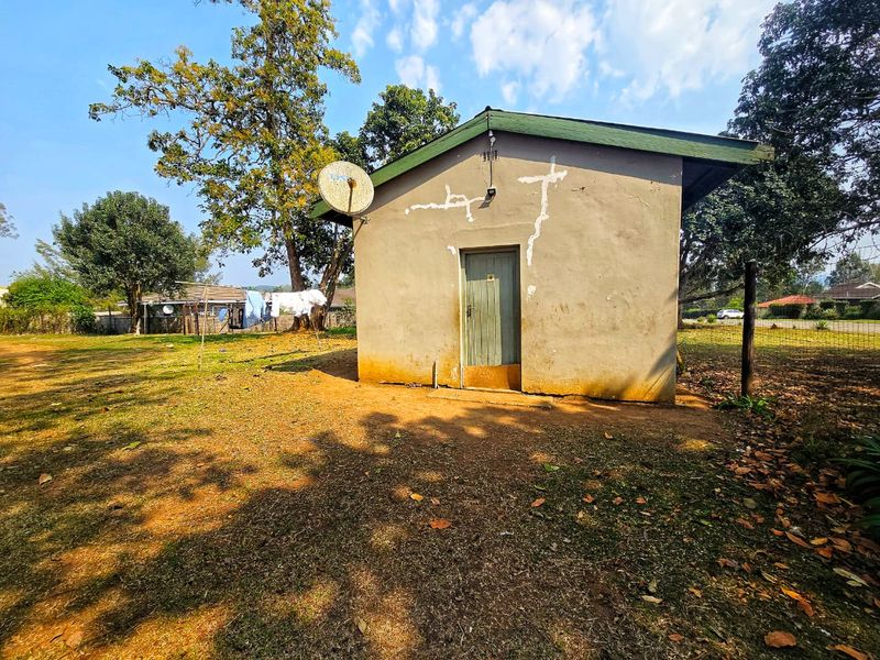 Rear view of a detached outbuilding featuring a single timber door, satellite dish, and visible exterior wall cracking and damp staining.