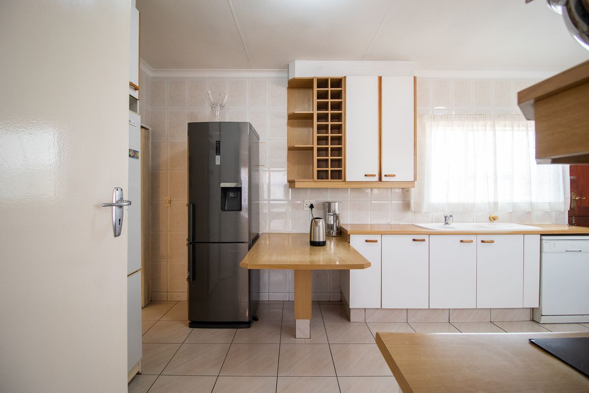 A functional kitchen featuring white cabinetry, tiled backsplash, tiled flooring, and a built-in breakfast counter, offering a clean and practical layout.