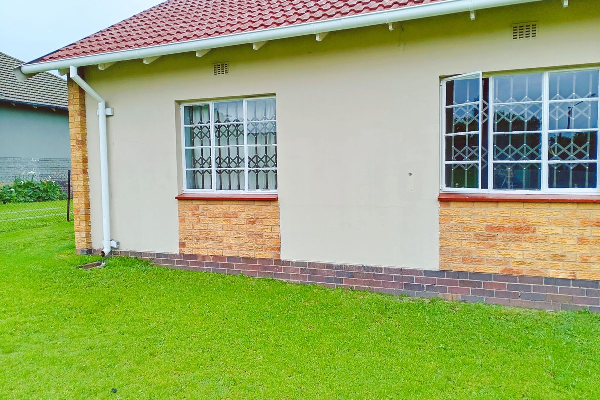 Side exterior view of the house featuring a tiled roof, brick base detailing, and security bars on the windows.