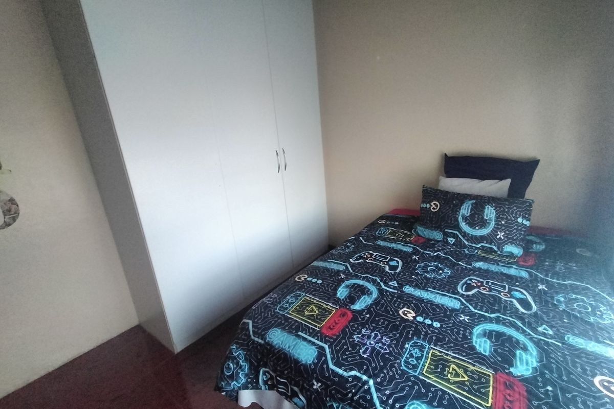 A functional bedroom featuring a white built-in wardrobe and tiled flooring.