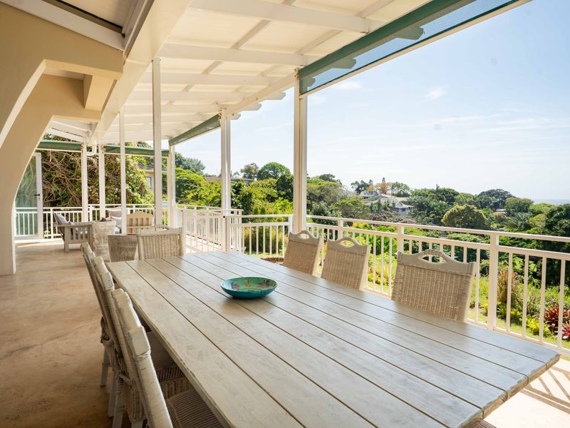 Spacious covered patio featuring concrete flooring and white railings, offering expansive views of the surrounding landscape.