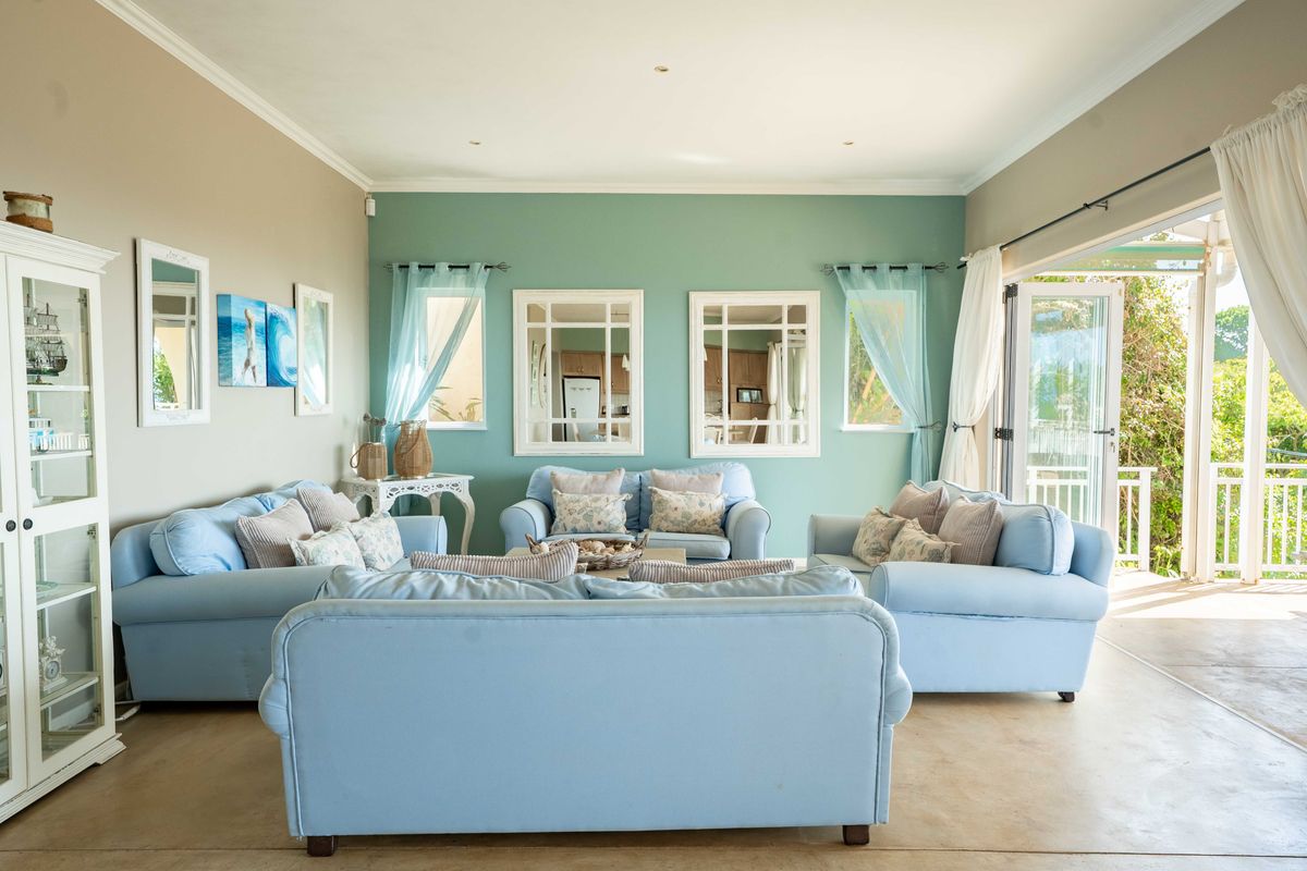 A bright and airy living room featuring polished concrete floors, recessed lighting, and large french doors opening onto an outdoor patio area.