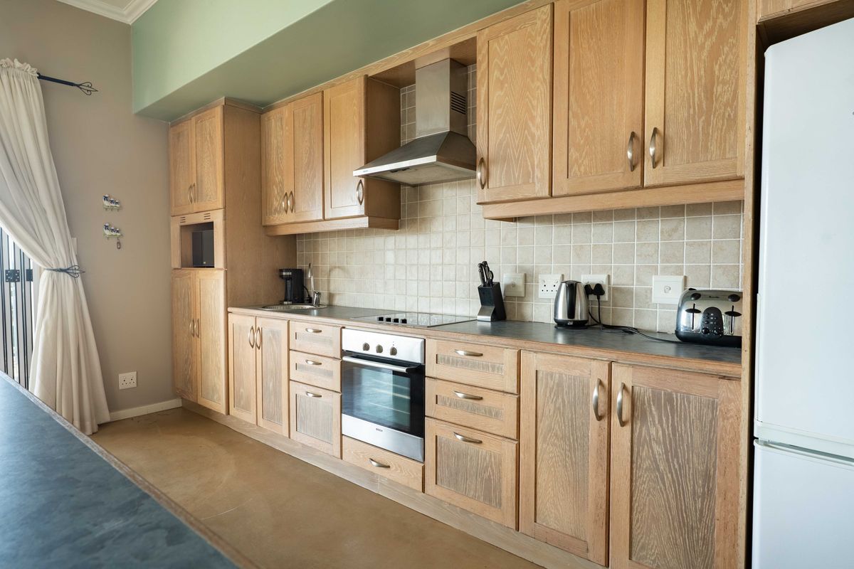 A functional kitchen featuring oak cabinetry, a built-in oven with extractor fan, tiled backsplash, and ample counter space.