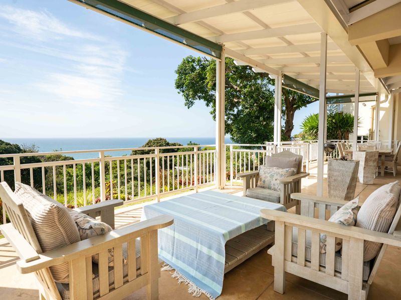 Spacious covered patio featuring tiled flooring and a timber roof structure, offering expansive ocean views and a comfortable outdoor living space.