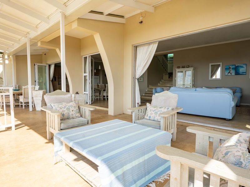 Spacious covered patio featuring exposed beam ceilings and seamless indoor-outdoor flow through large sliding glass doors into the main living area.
