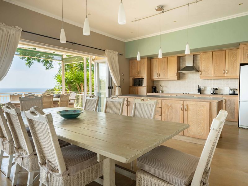 Spacious open-plan kitchen and dining area featuring light wood cabinetry, a central island, and seamless access to an outdoor patio with ocean views.