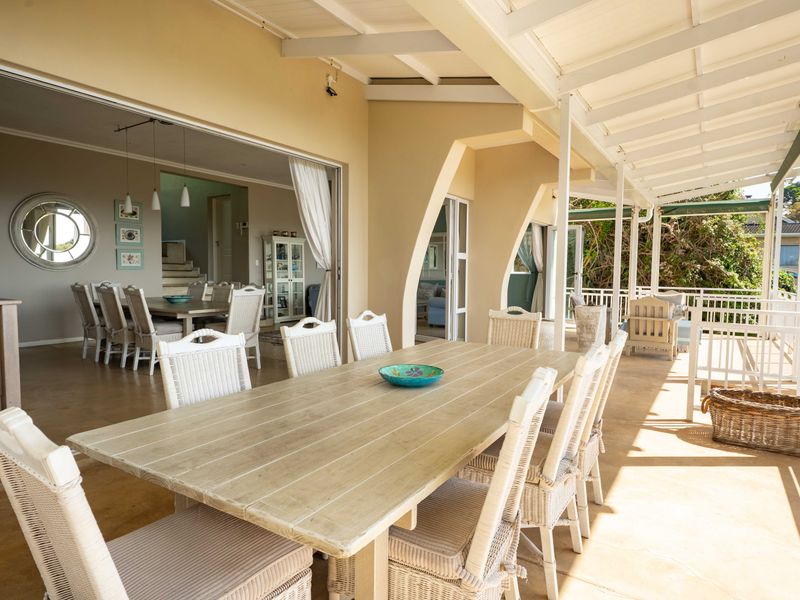 Spacious covered patio featuring an exposed beam ceiling and seamless transition to the interior dining area through large sliding glass doors.