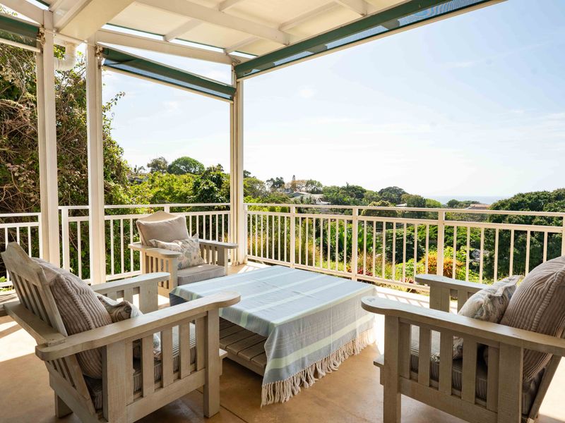 A covered outdoor patio featuring a protective railing and retractable awning, offering elevated views of the surrounding landscape.