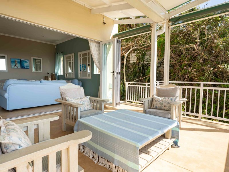 Covered outdoor patio featuring bi-fold doors that provide seamless indoor-outdoor flow, complete with a protective railing and retractable awning.
