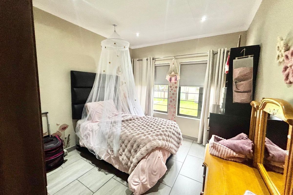 A well-lit bedroom featuring tiled flooring, recessed ceiling lighting, and large windows that provide natural light.