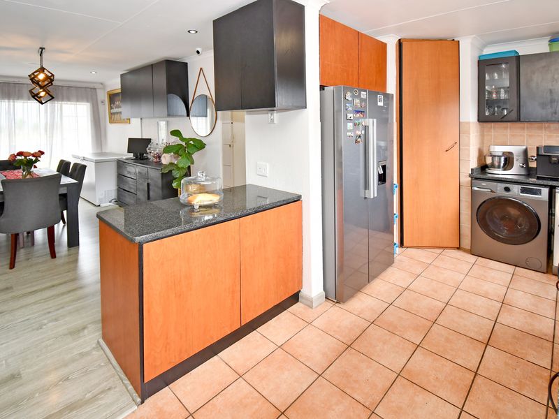 Open plan kitchen and dining area featuring a mix of laminate and tiled flooring, granite countertops, and ample built-in cabinetry.