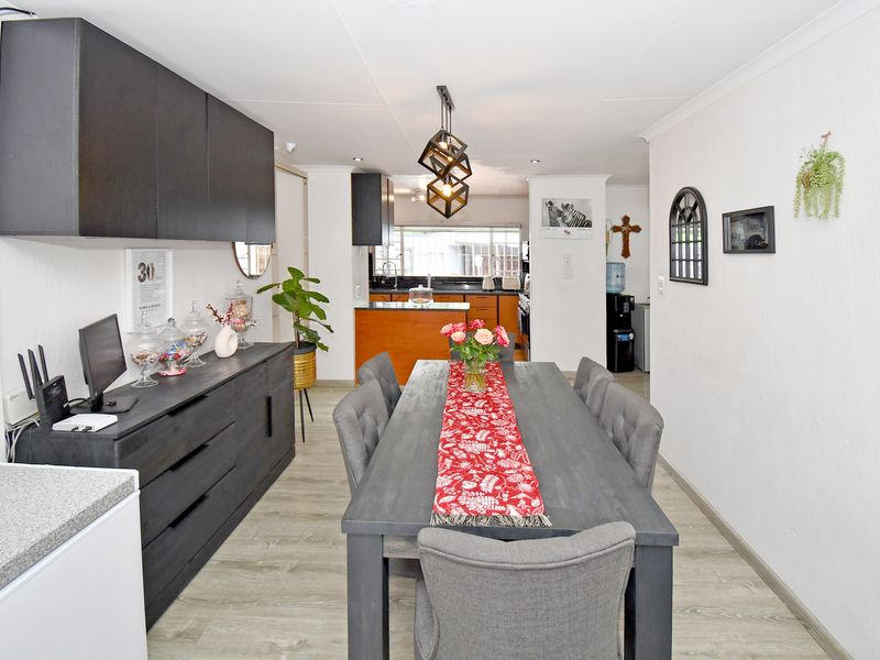 Open plan dining area featuring modern laminate flooring, recessed lighting, and built-in cabinetry, flowing seamlessly into the kitchen space.