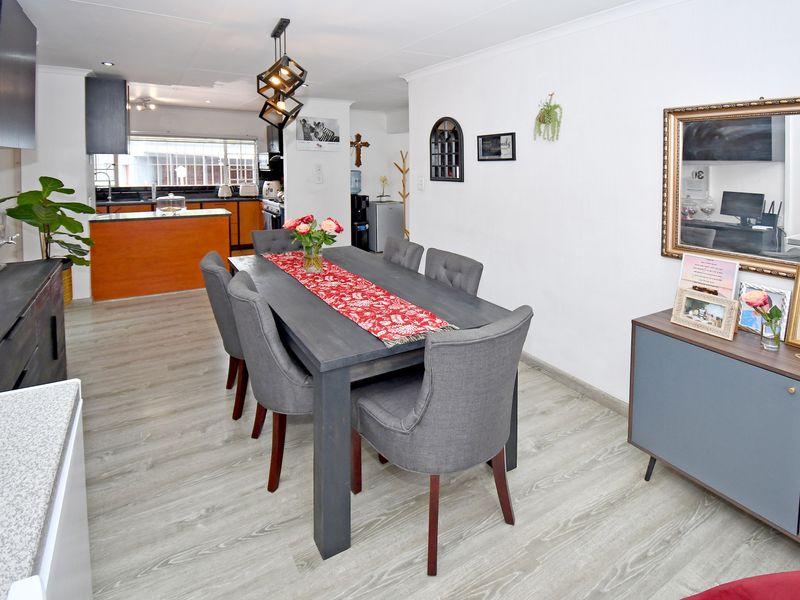 An open-plan dining and kitchen area featuring modern laminate flooring, contemporary cabinetry, and stylish pendant lighting, creating a functional and cohesive living space.