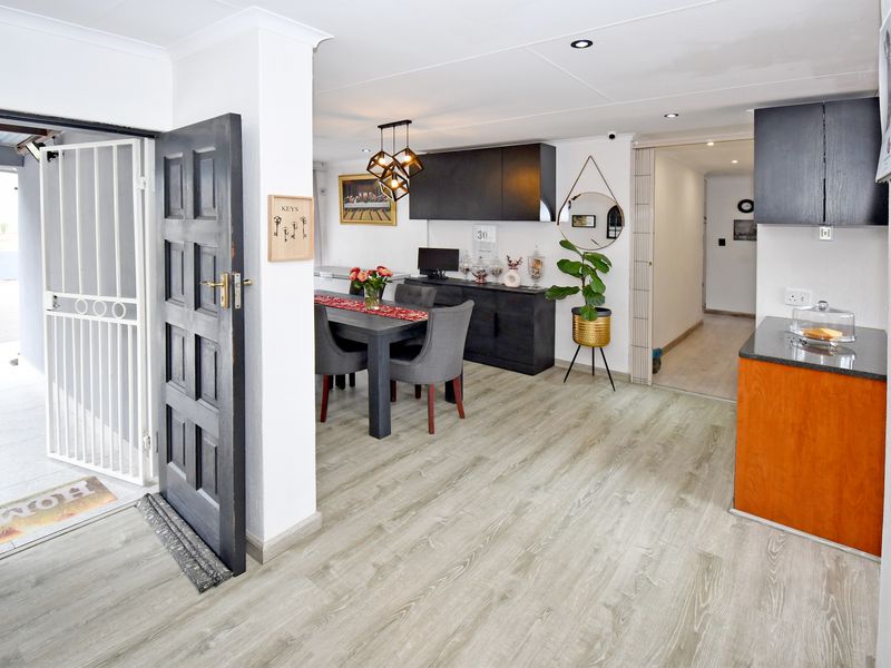 Open-plan living and dining area featuring modern laminate flooring, recessed lighting, and a functional kitchen with granite countertops and dark cabinetry.