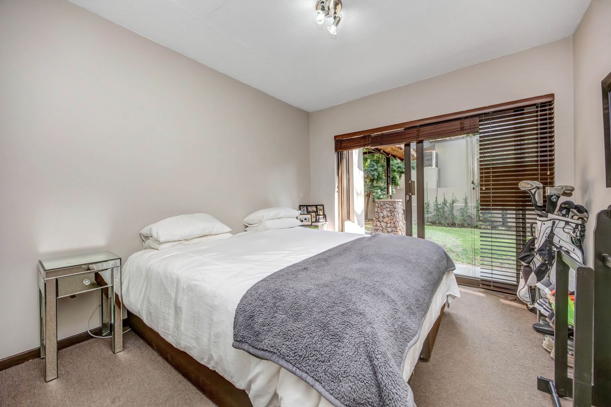 A bedroom featuring neutral wall tones, carpeted flooring, and sliding glass doors that provide direct access to the rear garden area.