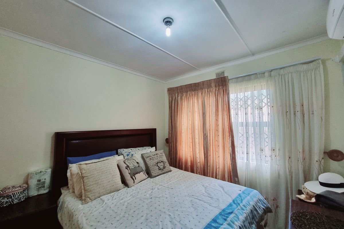 A standard bedroom featuring a window with security gate, curtain tracks, and a central ceiling light fixture.